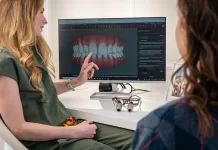 Jak wybrać odpowiedni moment na rozpoczęcie leczenia implantologicznego Dentystka omawia z pacjentką plan leczenia na ekranie zębów.
