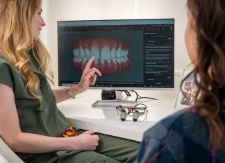 Jak wybrać odpowiedni moment na rozpoczęcie leczenia implantologicznego Dentystka omawia z pacjentką plan leczenia na ekranie zębów.